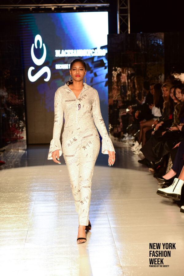 Woman wearing cute white newspaper printed jumpsuit with bell sleeves and front and back zipper